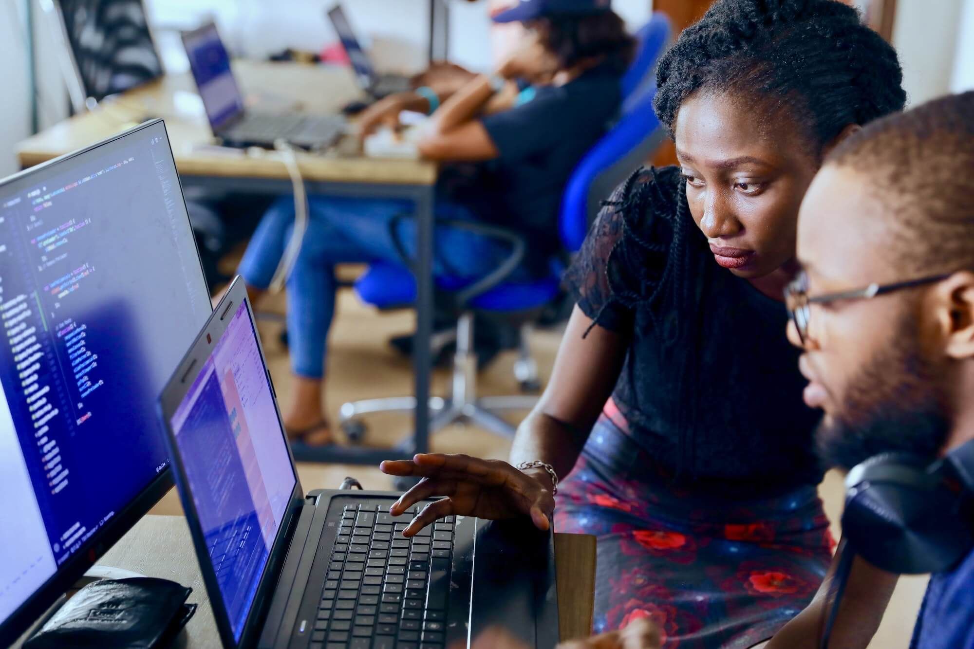 Two engineers reviewing code together at a laptop and a second monitor