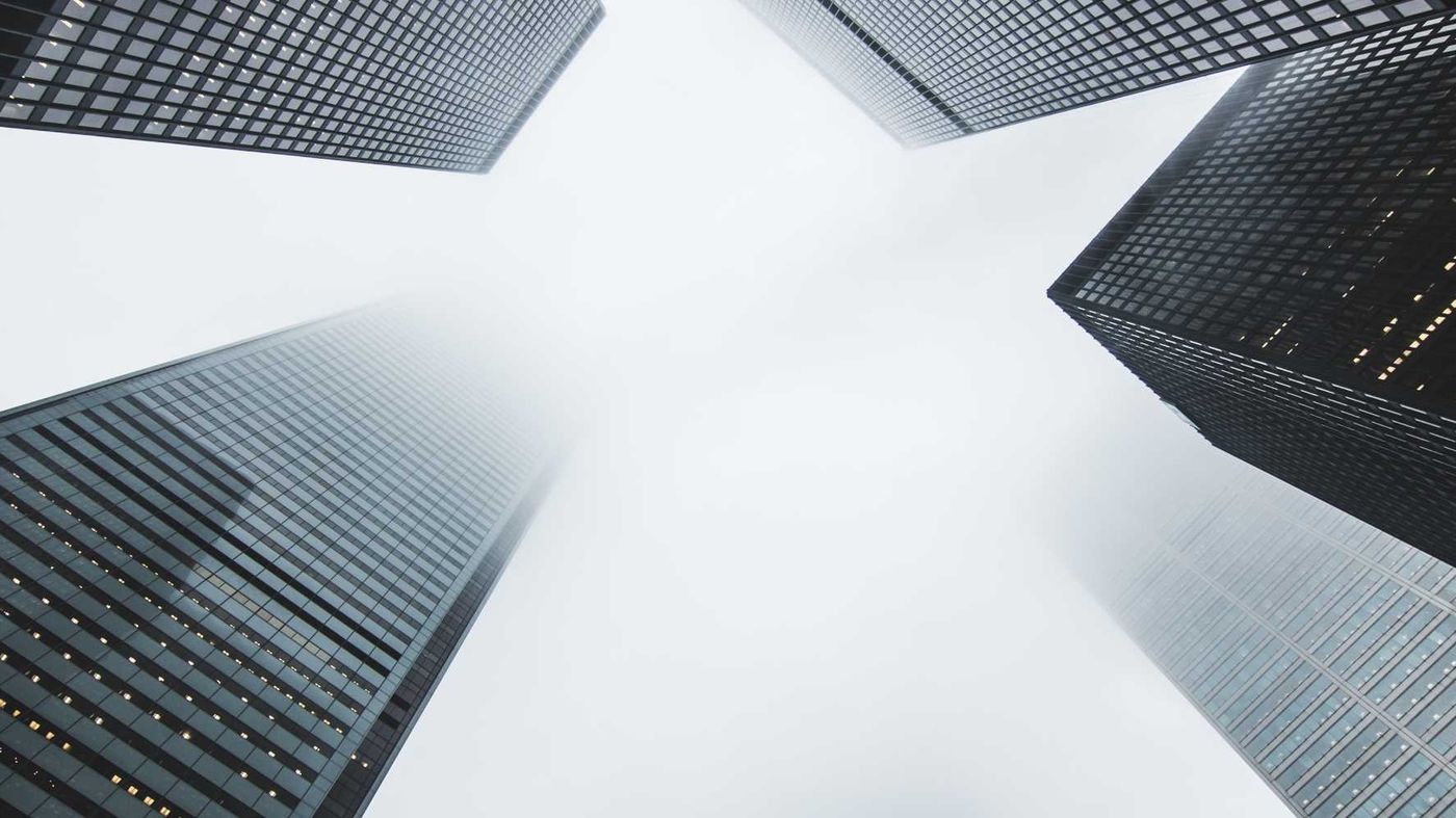 Glass office towers rising into low cloud